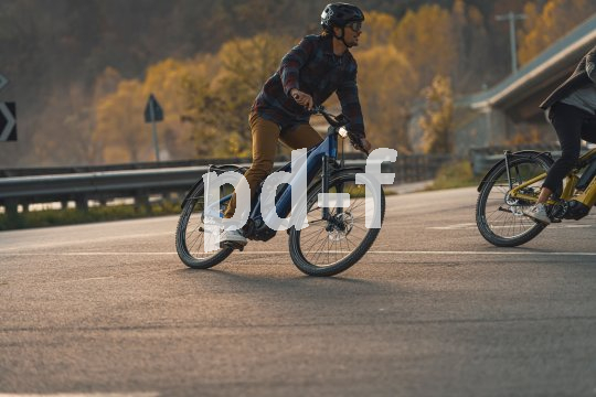 Mann fährt mit Fahrrad auf Landstraße durch eine Kurve.
