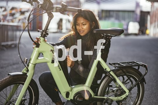 Eine Frau platziert den Akku eines E-Bikes im Rahmen.