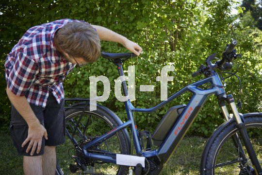 Ein Mann positioniert ein Schnurlot an der Spitze des Sattels an einem E-Bike.