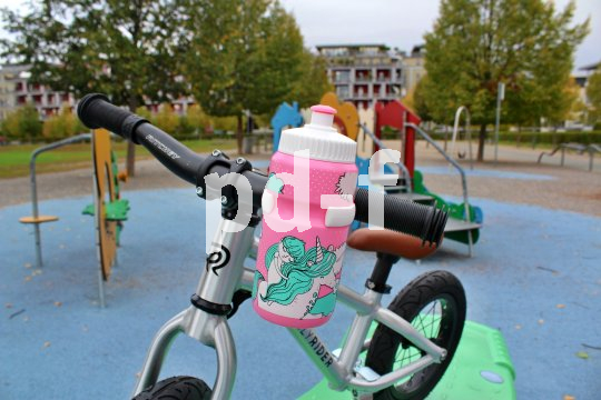 Eine rosa Trinkflasche am Lenker eines Kinderfahrrads montiert.
