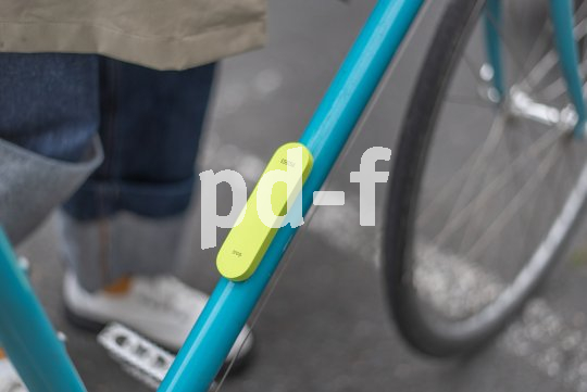 Ein neongelbes, längliches Objekt, das anstelle eines Flaschenhalters am Unterrohr eines Fahrrads montiert ist.