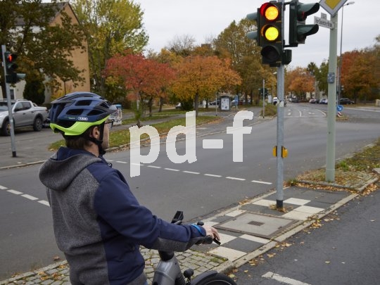 Ein Radfahrer steht an einer Ampel, die gerade umschaltet.