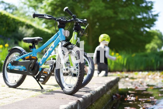 Zwei Kinderräder, die an einer Betonkante über einem Gewässer abgestellt sind.