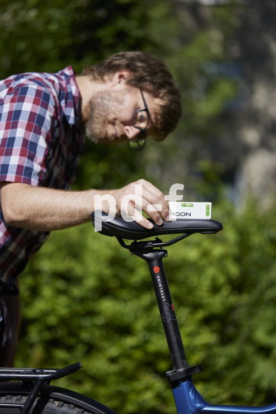 Ein Mann platziert eine kleine Wasserwage auf dem Sattel eines Fahrrads, um die Neigung zu überprüfen.