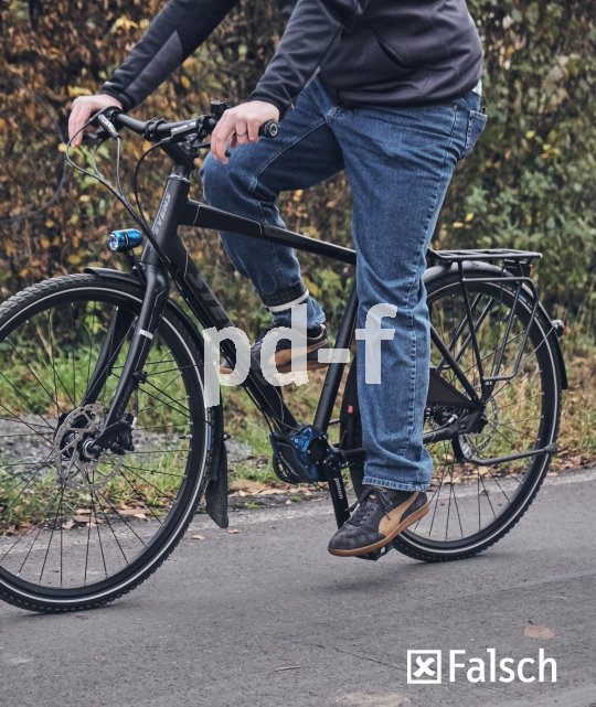 Eine Person fährt ein Fahrrad und streckt das linke Bein komplett durch, um treten zu können.