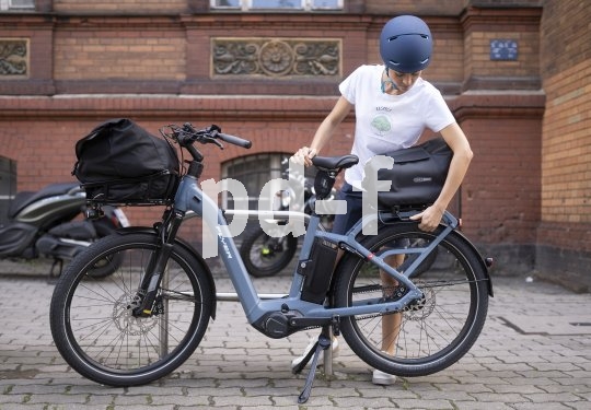 Eine Person steht neben einem E-Bike und befestigt eine Tasche auf dem Gepäckträger.