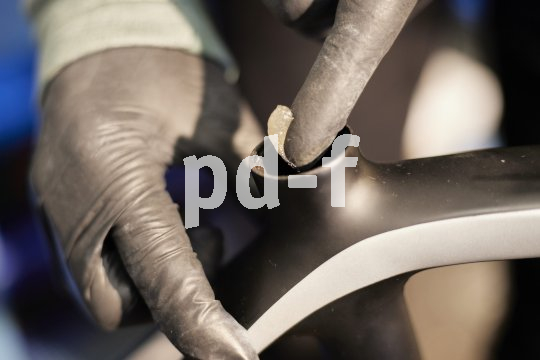 Detailaufnahme des Teils eines Fahrrades, wo die Sattelstütze eingesteckt wird. Eine Person trägt innen mit dem Finger eine helle Paste auf.