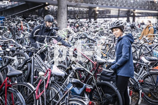 Zwei Personen mit Helmen stehen in einer großen Menge abgestellter Fahrräder.