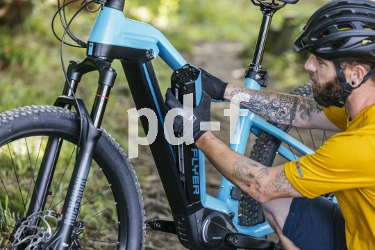 Ein Mann baut den integrierten Akku aus dem Rahmen eines E-Bikes aus.