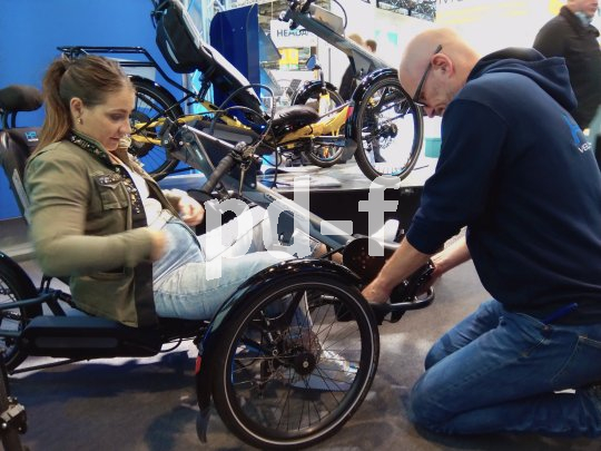 Die Sportlerin Kristina Vogel sitzt auf einem Trike mit Handkurbeln, das von einem Mitarbeiter des Herstellers HP Velotechnik angepasst wird.
