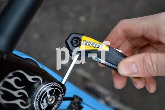 Ein Faltwerkzeug mit Innensechskantschlüssel in der Hand einer Person, die damit an dem Vorbau eines Fahrrades schraubt.