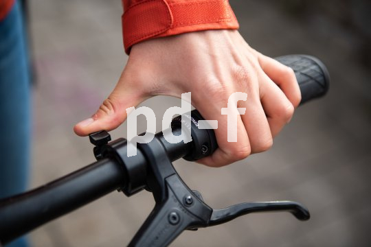 Detailaufnahme der Hand einer Person, die eine Fahrradklingel läutet.