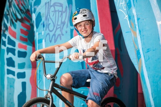 Ein Kind auf einem BMX-Rad vor Graffiti. 