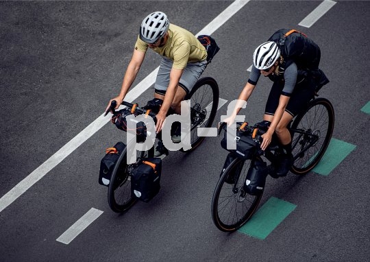 Draufsicht auf zwei Personen, die auf Fahrrädern mit Gepäck auf einer Straße fahren.