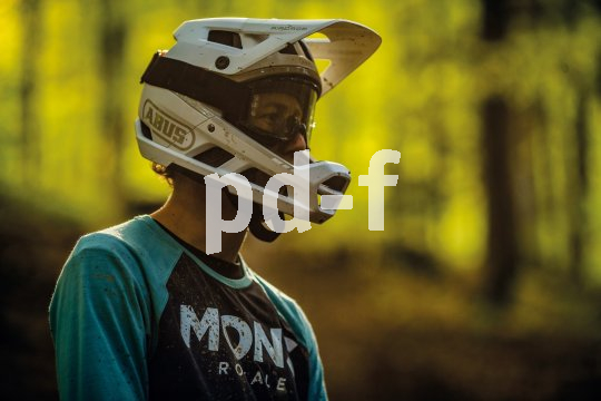 Mann trägt Fullface-Helm in Wald beim Mountainbiken.