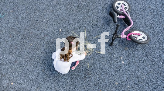 Ein Kind hockt neben einem Laufrad und malt mit Kreide auf dem Boden.