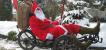 Eine als Weihnachtsmann verkleidete Person auf einem Liegedreirad.