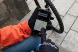 Ein Smartphone mit einer Navigations-App in der Hand einer Person mit Handschuhen.
