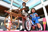 Ein Kind mit einem Laufrad vor einem Mann mit einem historischen Laufrad aus Holz.