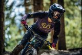 Frau mit Helm und Brille fährt mit Mountainbike durch Wald 