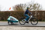 Mann fährt mit E-Bike und Kinderanhänger