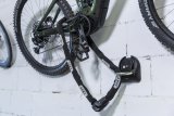Ein an einer Wand hängendes Fahrrad ist mit einem Fahrradschloss an einer darunter angebrachten, festen Verankerung gesichert.