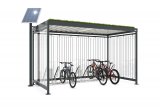 Ein überdachter Fahrradstellplatz mit Grünfläche auf dem Dach und einer Solarzelle daneben.